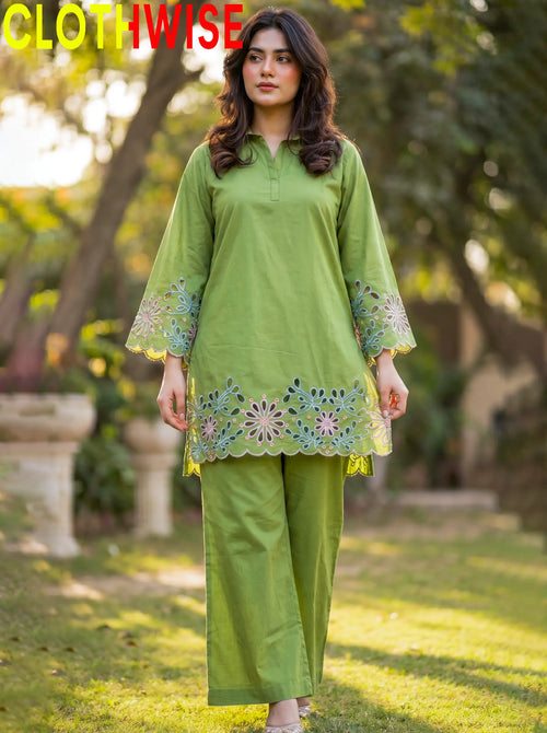 Woman wearing a green traditional outfit with floral embroidery in an outdoor setting.