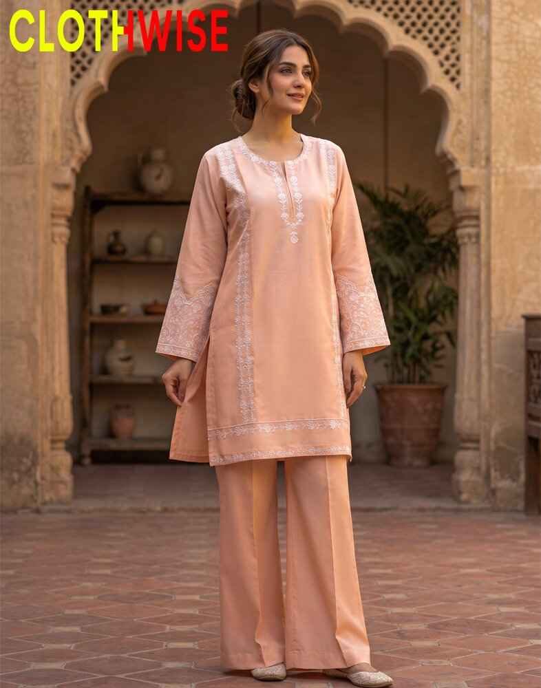 Woman wearing a peach traditional outfit with intricate patterns in an outdoor setting.
