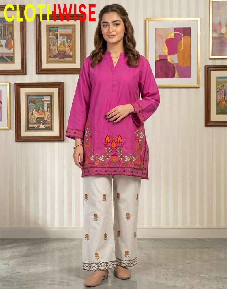 Woman wearing a pink embroidered outfit in a room with framed paintings on the wall.
