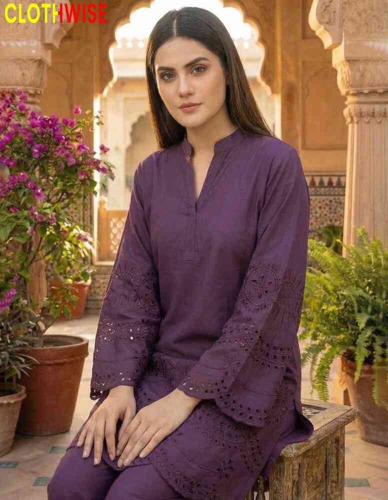 Woman in a purple outfit sitting in an outdoor setting with plants and architectural elements.