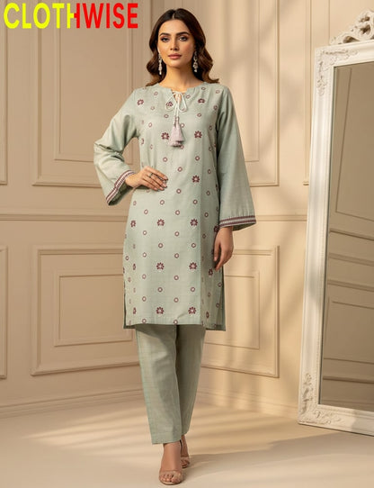 Woman wearing a light green kurta with floral patterns in a room with a mirror.