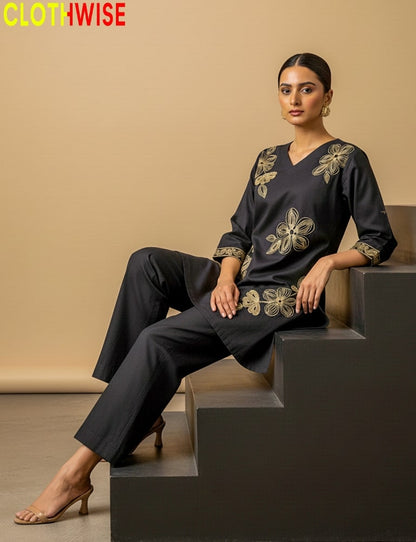 Woman wearing a black outfit with gold embroidery sitting on steps, with 'ClothWise' branding.