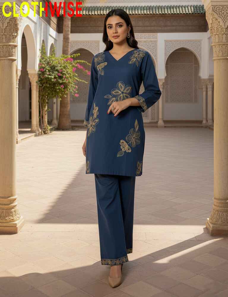Woman in a blue embroidered outfit standing in a courtyard with columns and plants.