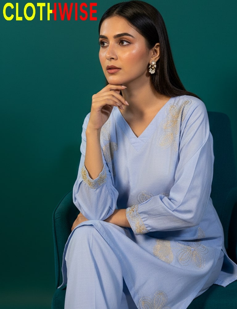 Woman wearing a light blue embroidered outfit with a green background, featuring the 'ClothWise' brand.