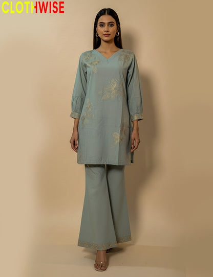 Woman wearing a light blue embroidered outfit with wide-leg pants on a beige background, branded 'Clothwise'.