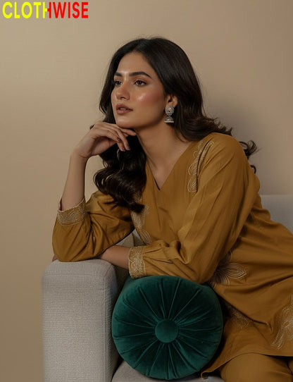 Woman in a mustard yellow outfit sitting on a couch with a green pillow, branded 'CLOTHWISE'.