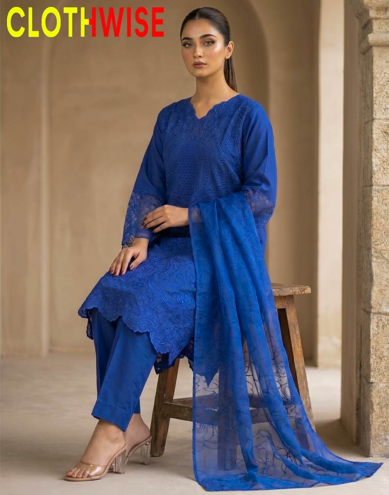 Woman in a blue outfit with a matching dupatta, sitting on a stool indoors.