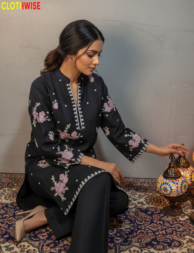 Woman in black embroidered outfit sitting on a patterned rug with a decorative lamp.