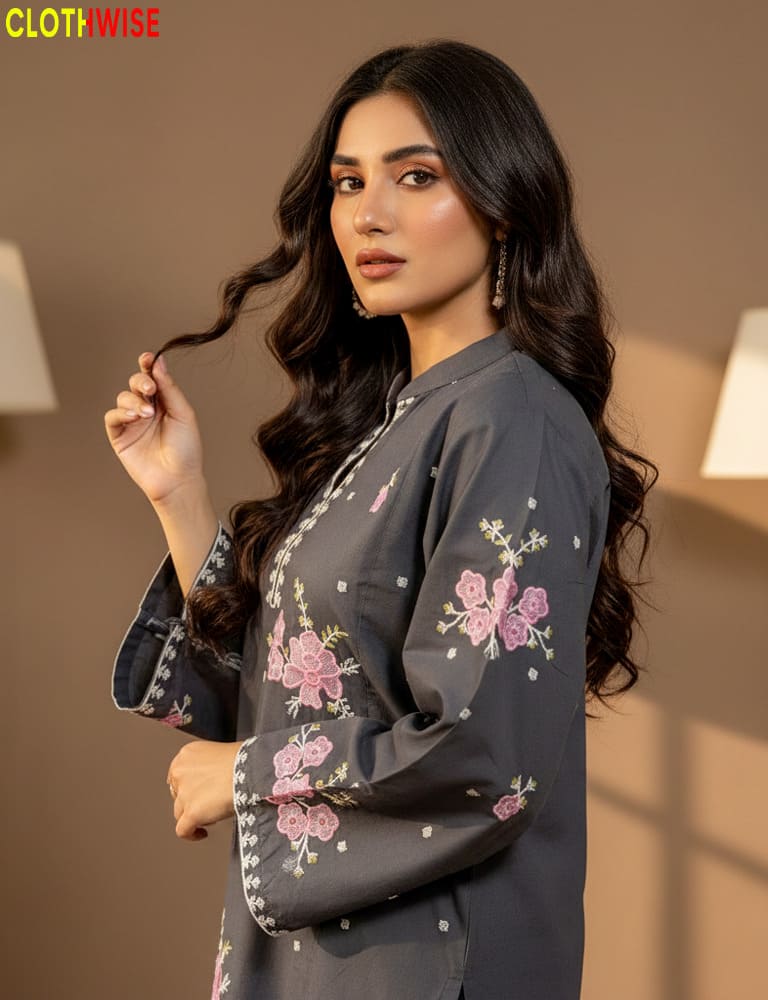 Woman wearing a dark gray outfit with floral embroidery, posing indoors.