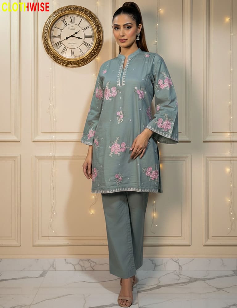 Woman wearing a light blue embroidered kurta with gray pants in a decorated room.