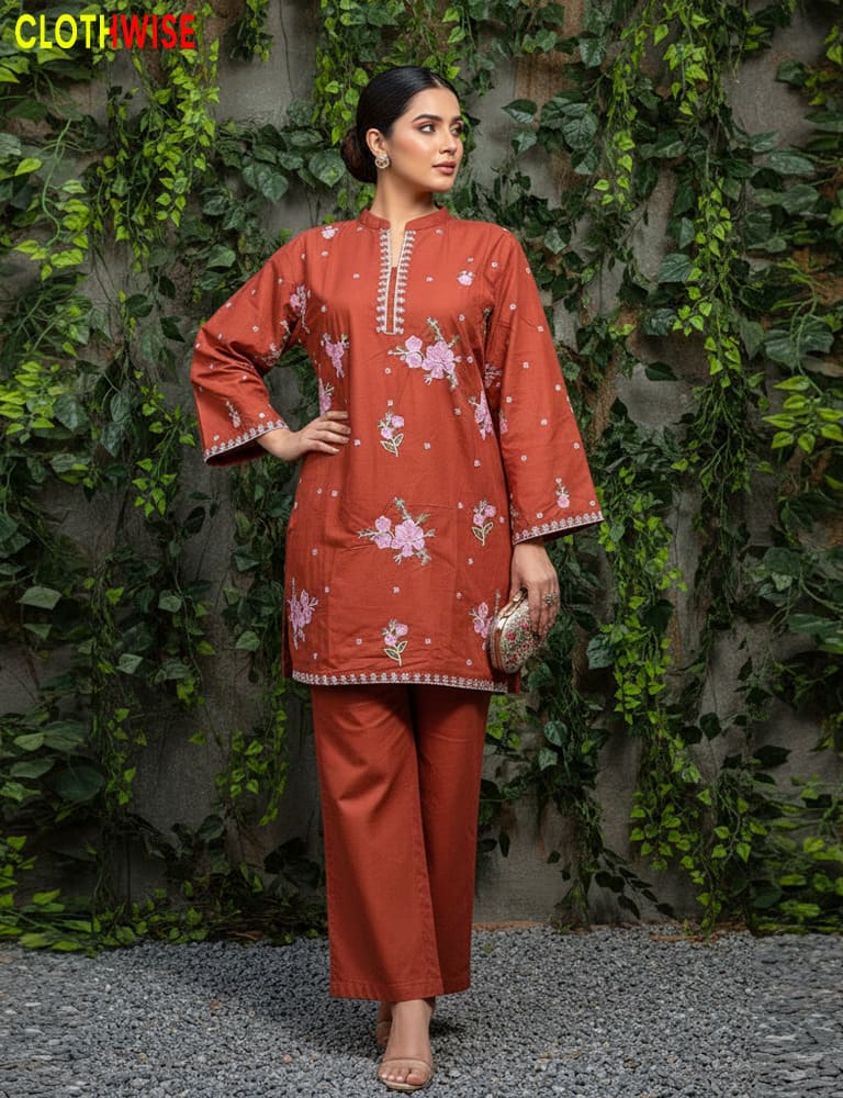Woman wearing a rust-colored traditional outfit with floral patterns against a green leafy background.