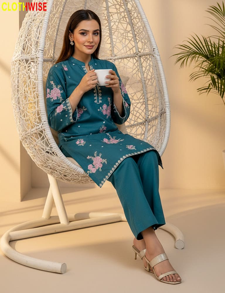 Woman in a teal outfit with floral patterns sitting in a wicker chair, holding a cup.