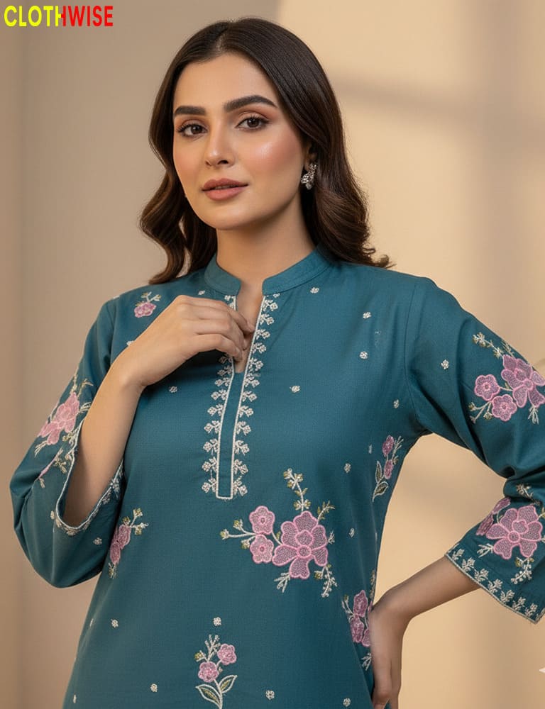 Woman wearing a teal embroidered dress with pink flowers against a beige background