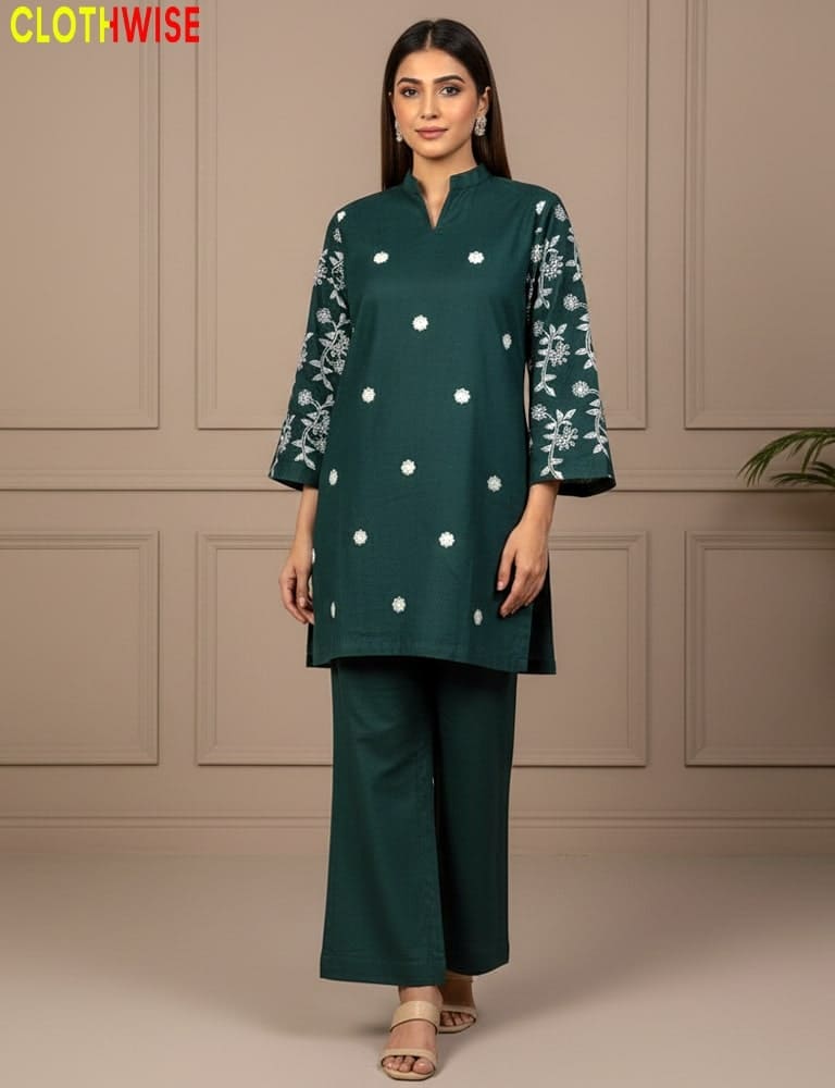 Woman wearing a green outfit with white patterns against a beige wall.