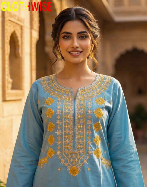 Woman wearing a blue embroidered traditional outfit with a blurred architectural background