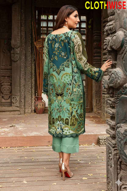 Woman in a green and teal embroidered outfit standing in front of an architectural structure.