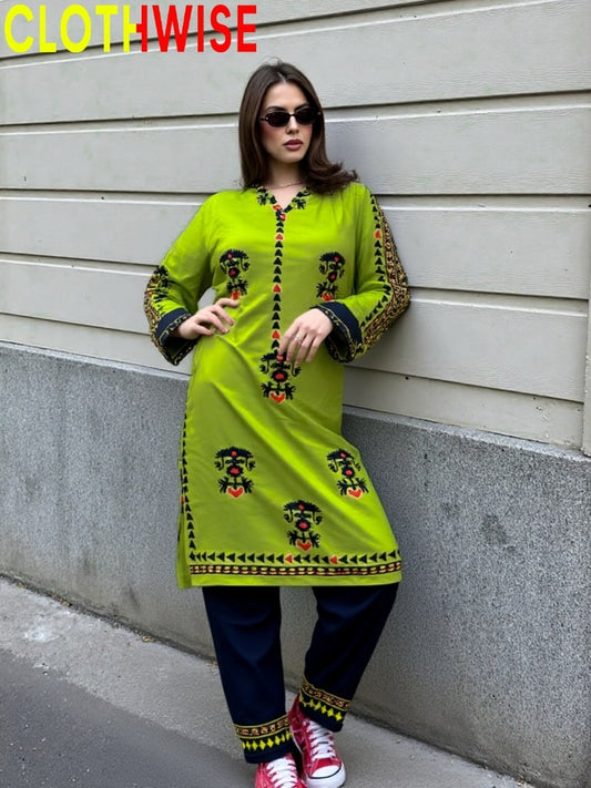 Woman wearing a bright green printed outfit against a gray wall