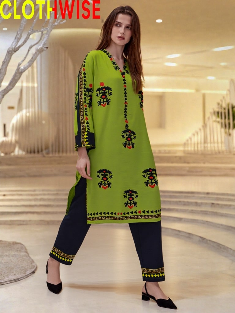 Woman wearing a green and black embroidered outfit in a modern indoor setting with 'CLOTHWISE' branding.