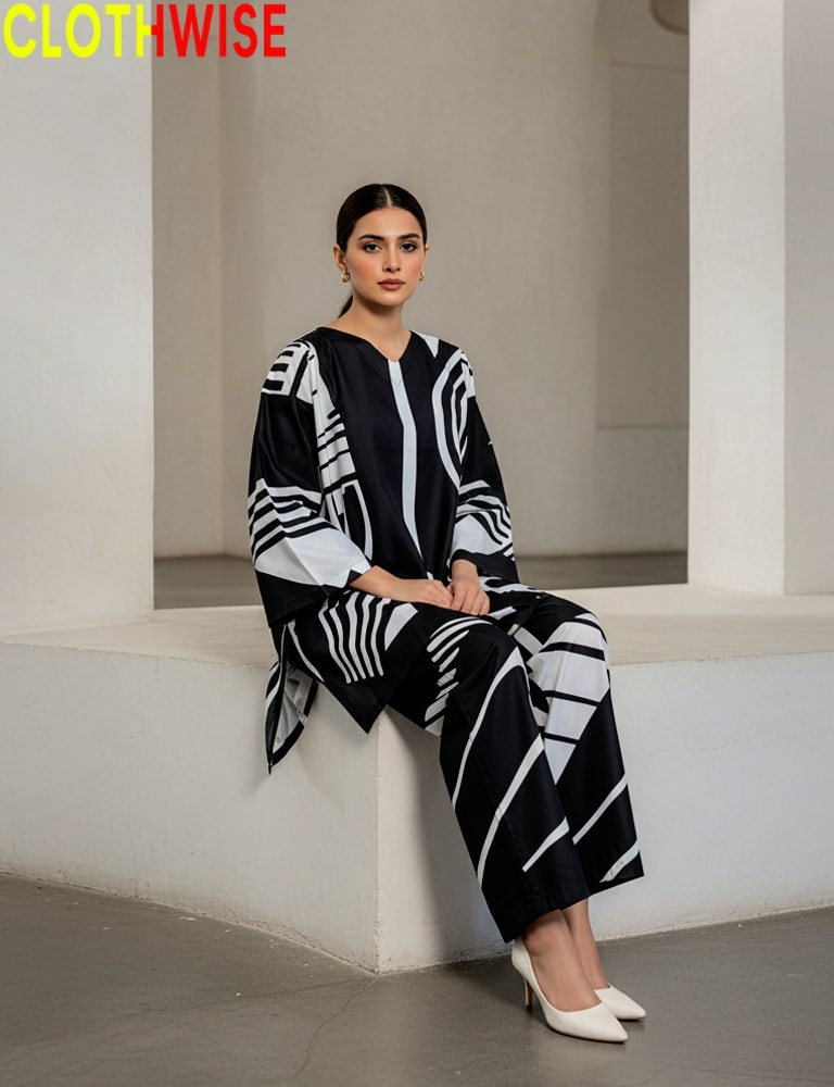 Woman wearing a black and white patterned outfit sitting on a white ledge.