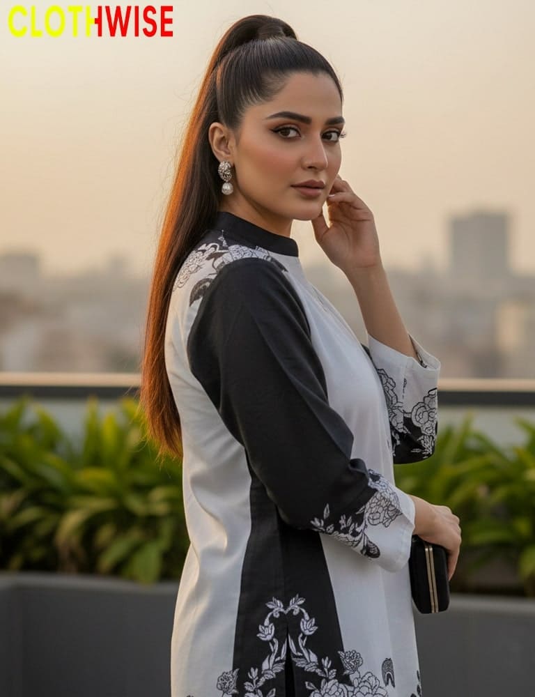 Woman wearing a black and white outfit with floral embroidery, standing on a rooftop with a cityscape background.