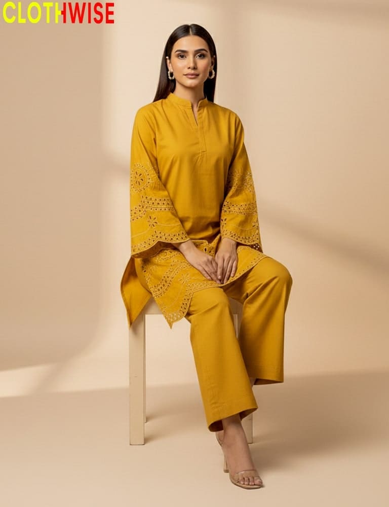 Woman wearing a mustard yellow outfit with intricate designs, sitting on a chair against a beige background. Brand 'CLOTHWISE' visible.