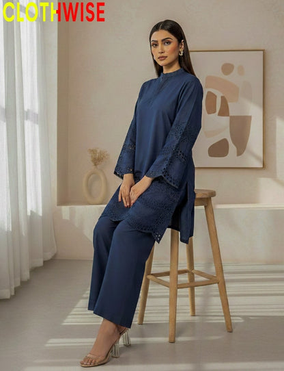 Woman in a blue outfit sitting on a stool in a room with abstract art on the wall.