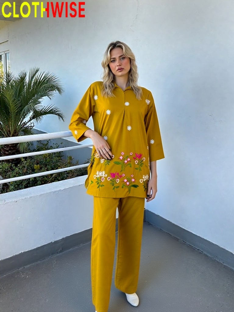 Woman wearing a mustard yellow outfit with floral patterns on a balcony.