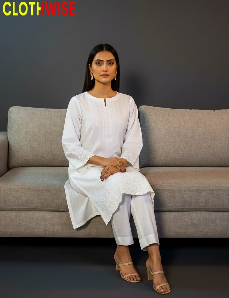 Woman sitting on a gray sofa wearing a white outfit with 'CLOTHWISE' branding.