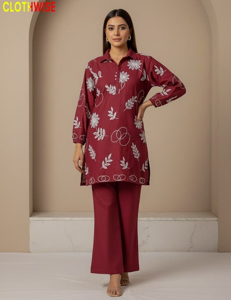 Woman wearing a maroon outfit with white floral patterns in a neutral setting