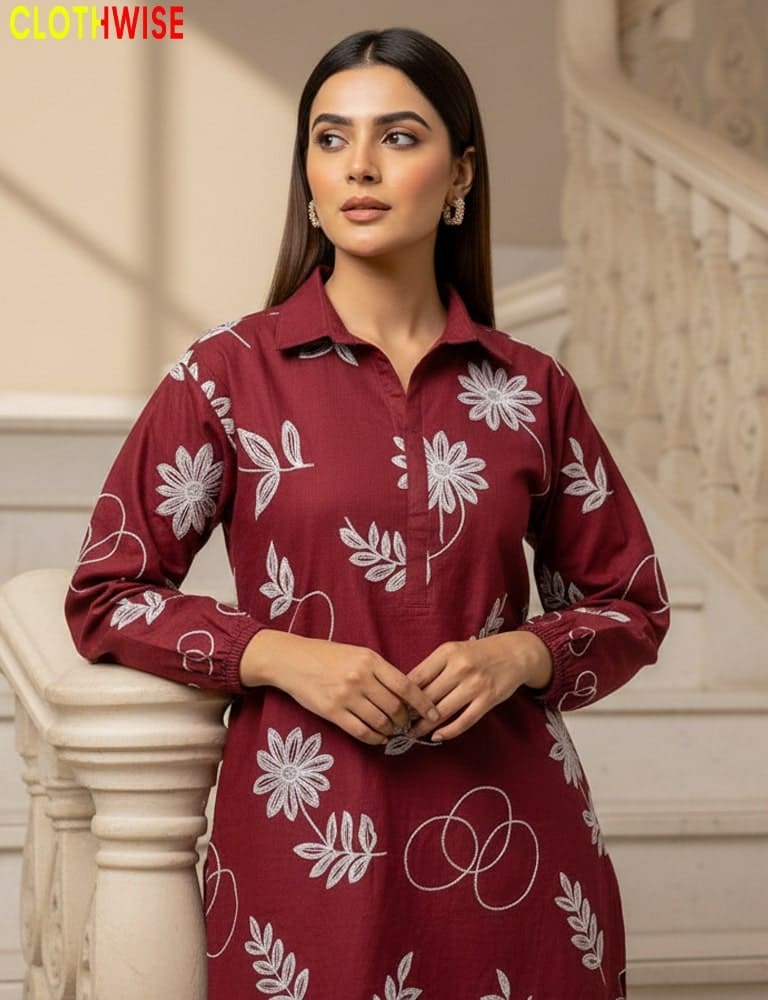 Woman wearing a maroon dress with white floral patterns in an elegant indoor setting.