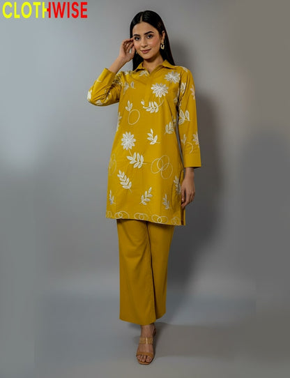 Woman wearing a mustard yellow outfit with floral patterns on a gray background, branded 'CLOTHWISE'.