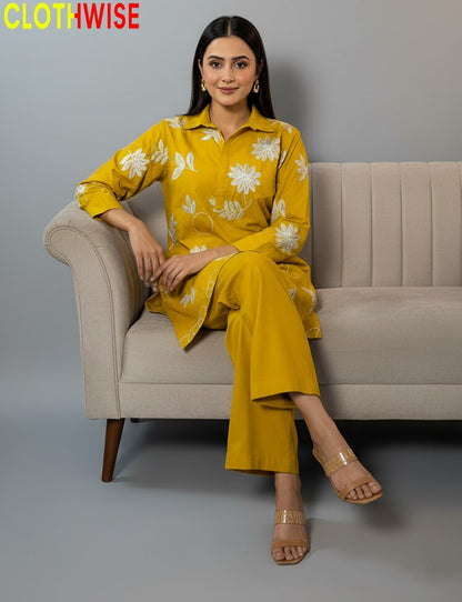 Woman in a yellow outfit with floral patterns sitting on a beige couch, branded 'CLOTHWISE'.
